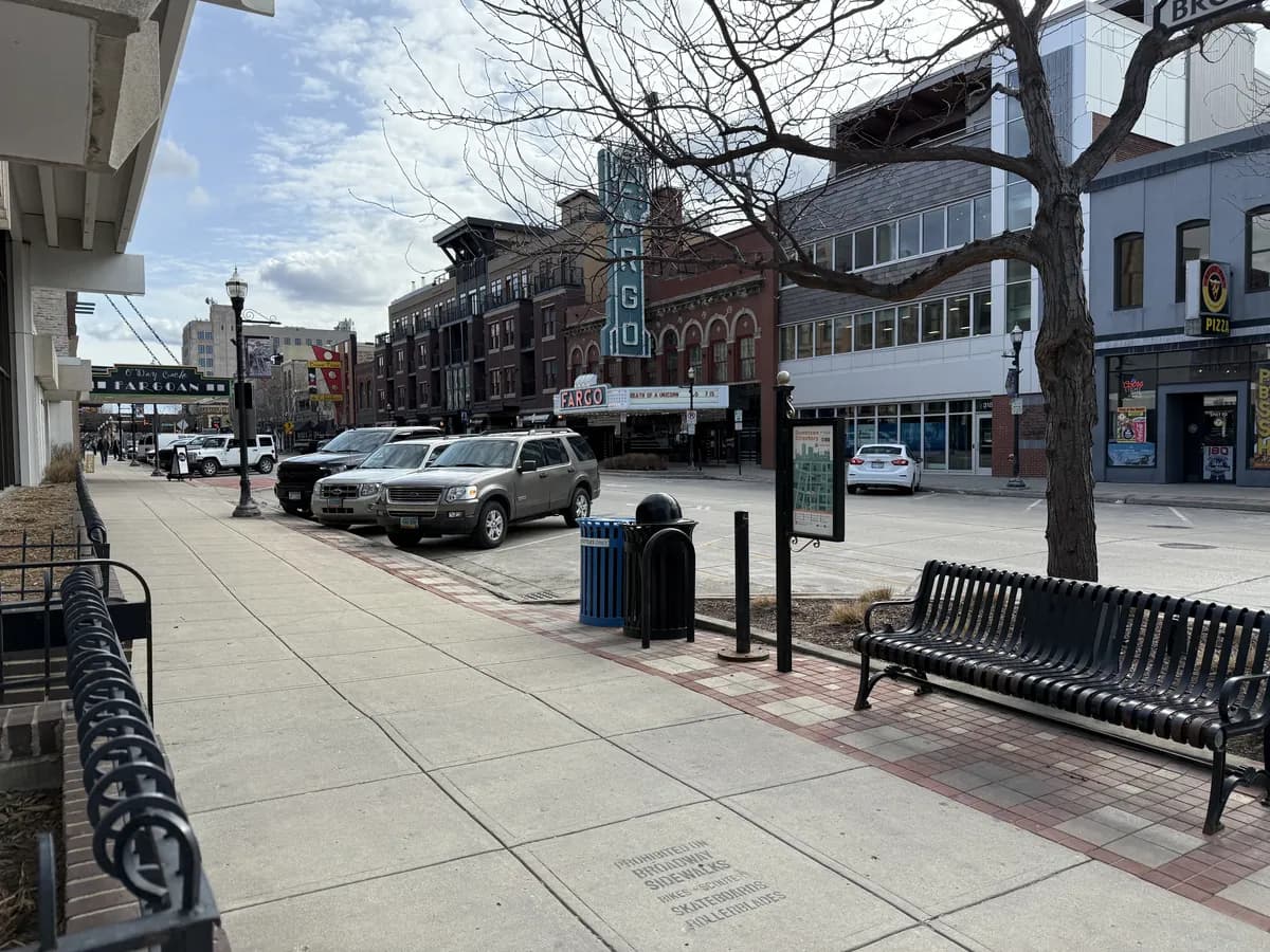 A bench and bare trees on the Broadway sidewalk in downtown Fargo